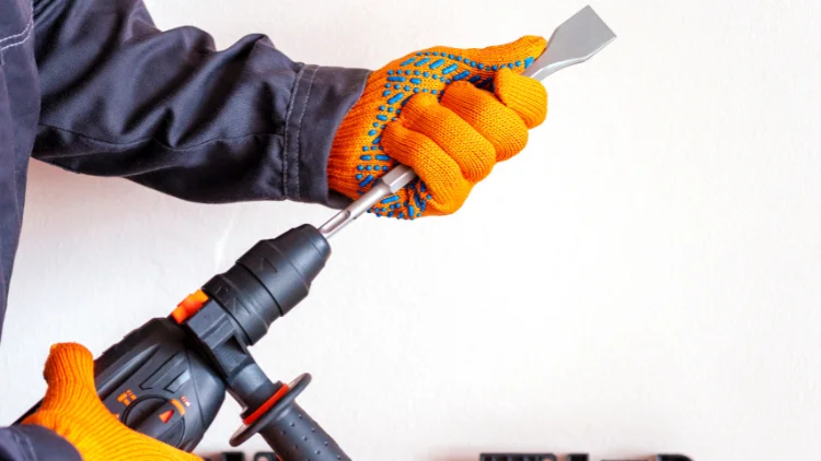Worker holding rotary hammer with chisel bit and safety gloves