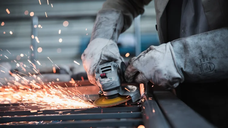Worker using angle grinder on metal.