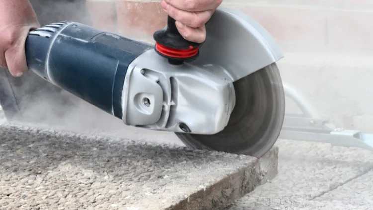 Angle grinder cutting concrete pavement